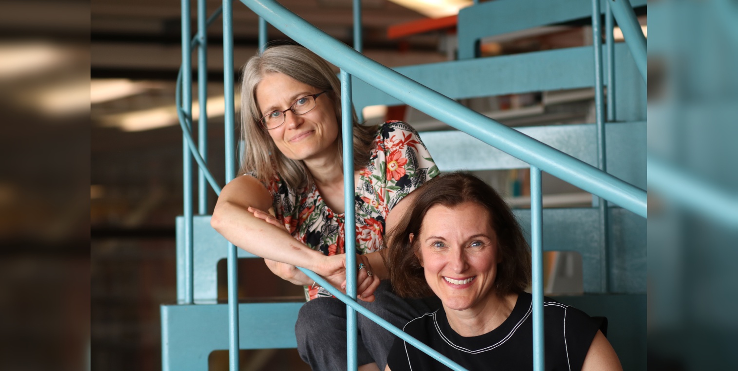 Dr. Tracy Whalen, Acting Dean, and Dr. Anne-Laurence Caudano, Acting Associate Dean, pictured on the spiral staircase in the UWinnipeg library.