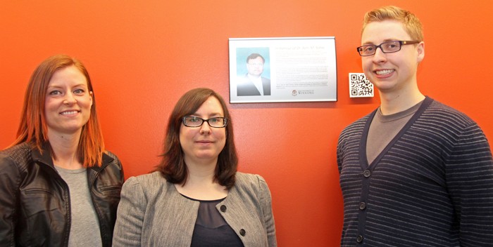 Three people stand in front of an orange wall