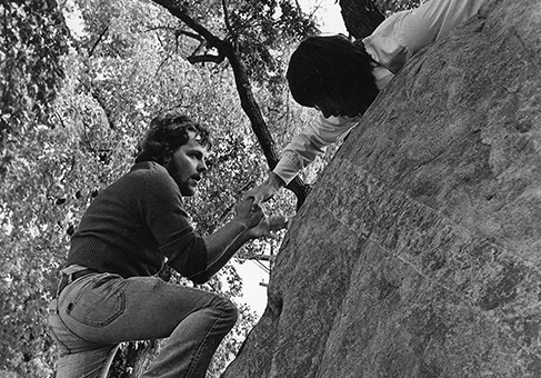 Black and white image of Rock Climb participant being filmed by a video camera.