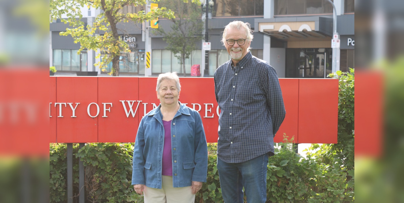 2 Students standing on the front lawn smiling at camera