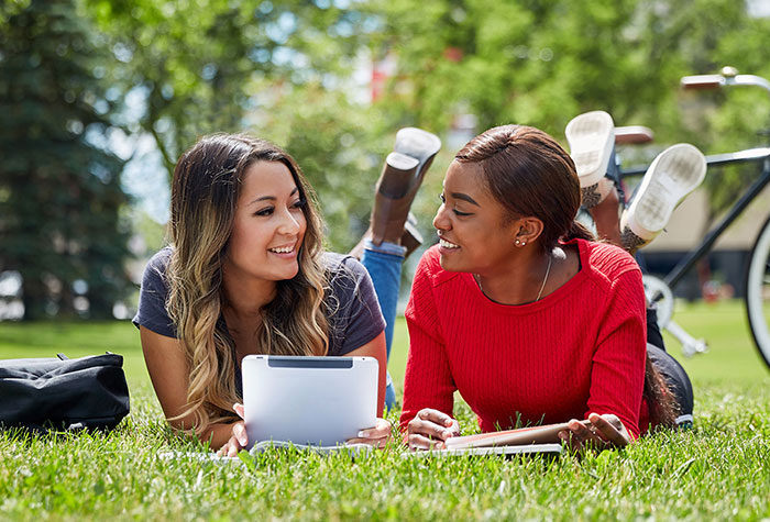 Two students talking on front lawn