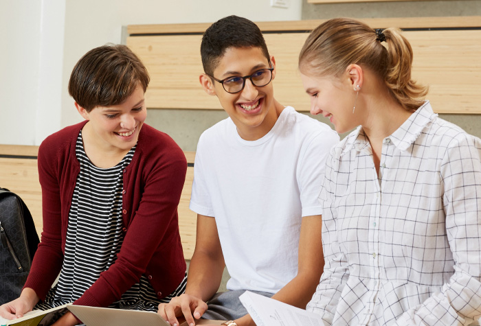 Three students laughing while sitting together
