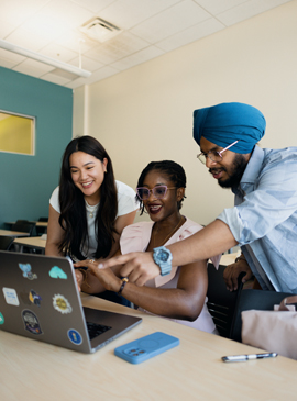 Three students looking at a laptop. 