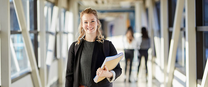 Student stands holding books