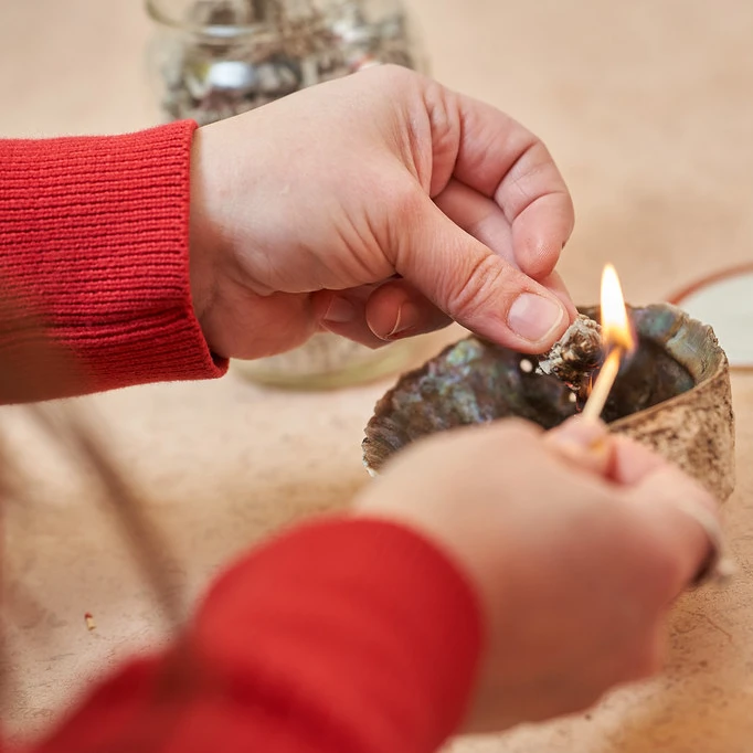 Close up of hands lighting a smudge in a bowl