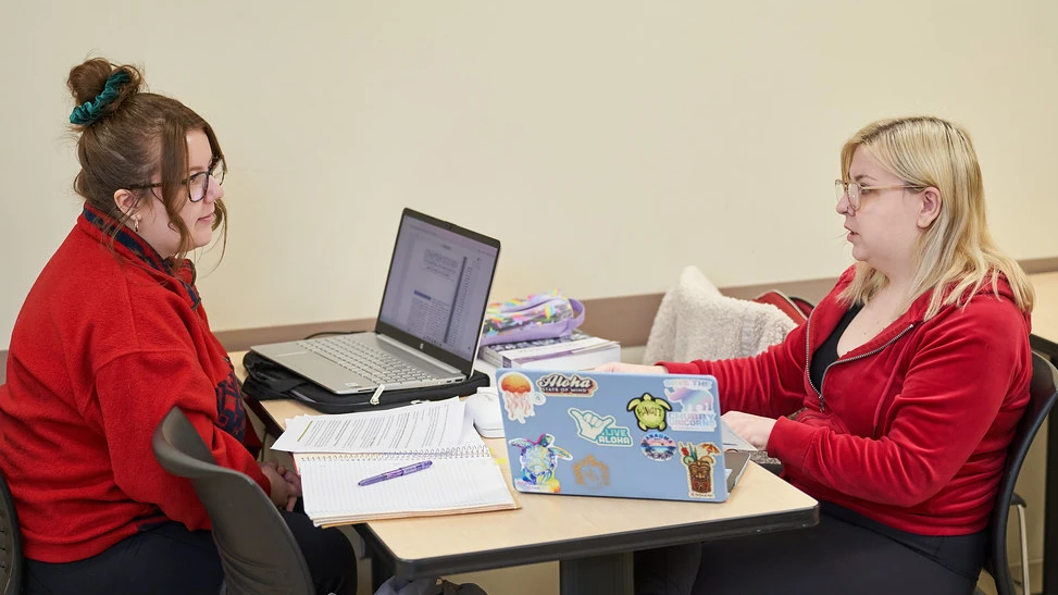 Two students at a desk talking