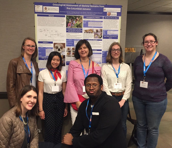 Students and Mirjana Roksandic standing in front of the winning poster at the CAA conference