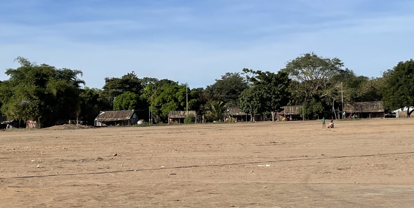 A field of sand with houses in the background