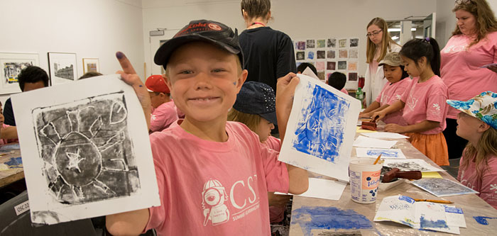 a child holds up two prints he made an art workshop in gallery 1c03