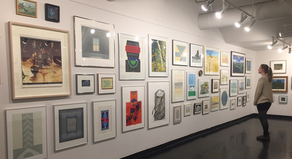 a woman looks at art hung on the wall in Gallery 1C03