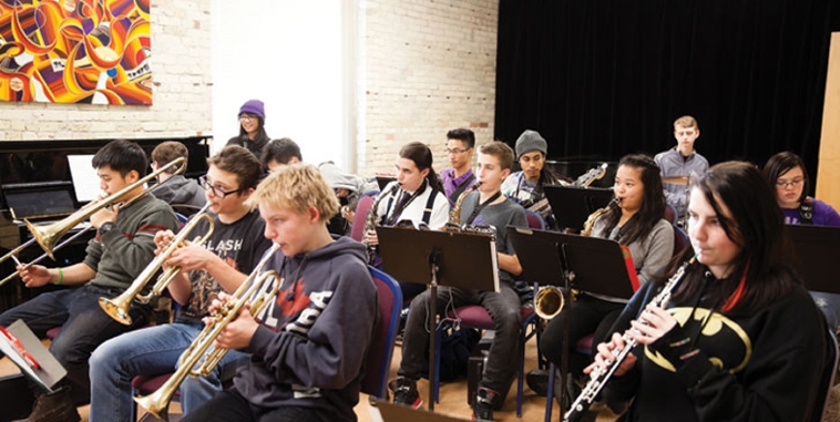 Collegiate students play instruments in a band class