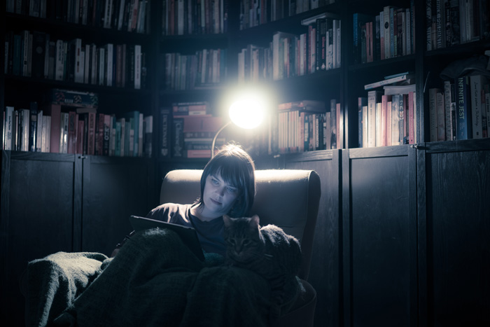 Woman reading in the light of a lamp.