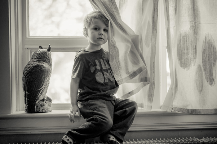 young child sitting on window ledge