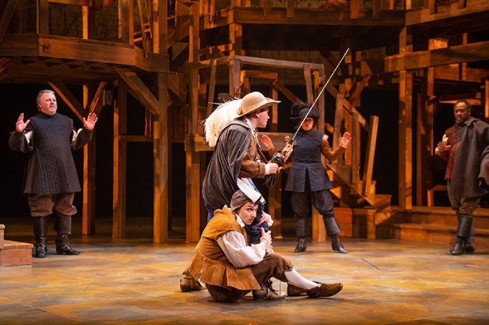Planchet (Tristan Carlucci) clings to D'Artagnon's (Melissa Langdon's) leg.