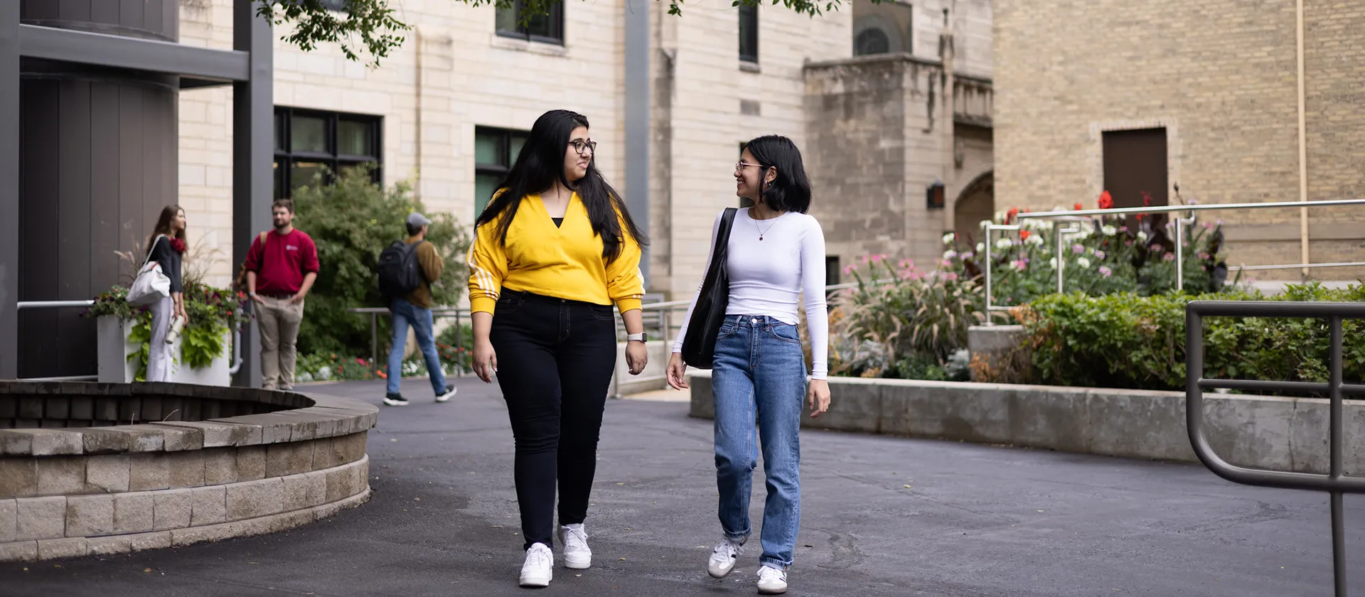Two students walking and talking outside on campus.