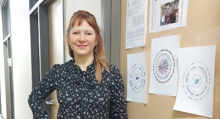 Dr. Sara Good stands in front of a bulletin board