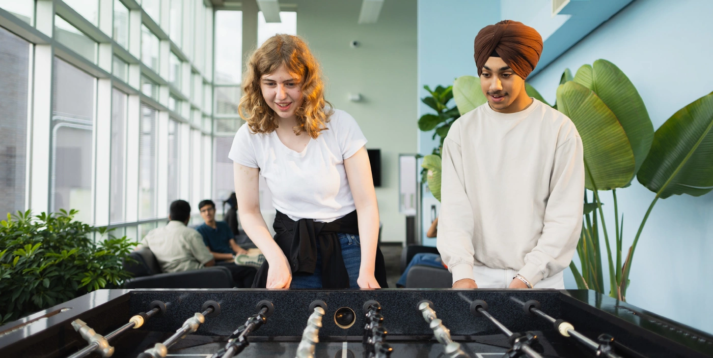 Two students play foosball in McFeetors Hall lounge