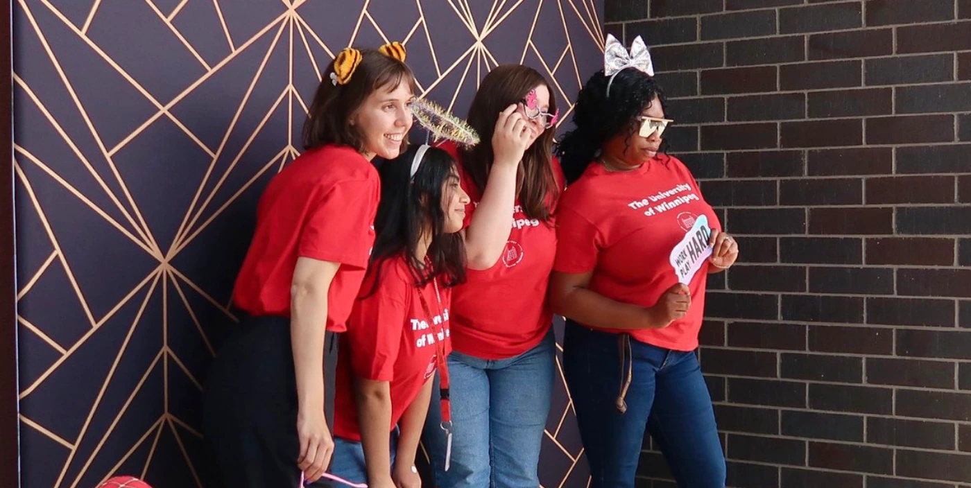 Four people holding props stand in front of a photo background