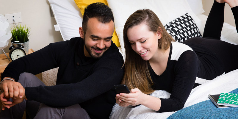 People sitting in dorm room looking at phone