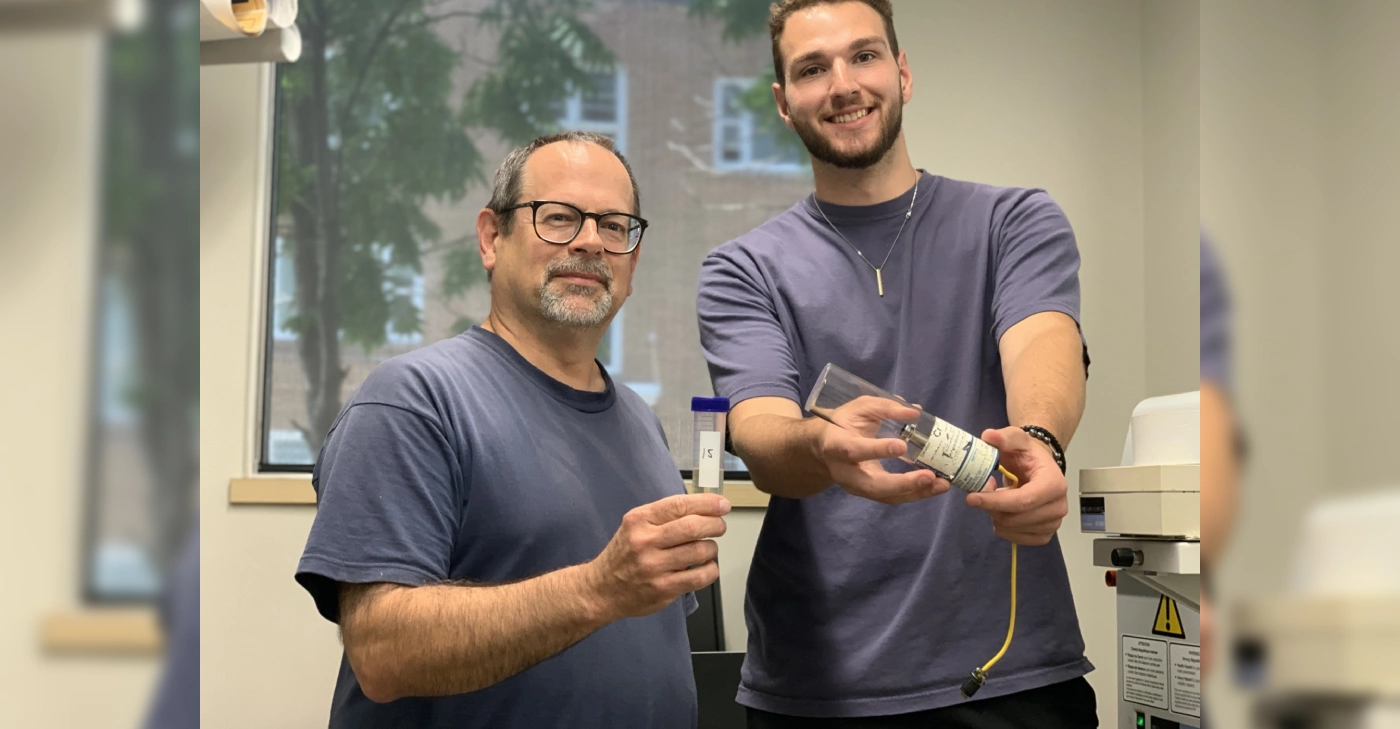 Doug Goltz and student Jaxon Rose stand together, smiling, in a research lab