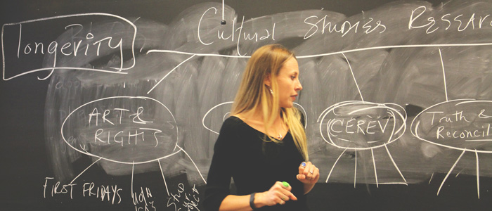 Jen Clary Lemon in front of a chalkboard talking to a class