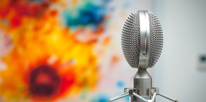 Photo of a microphone with a colourful art piece in the background.
