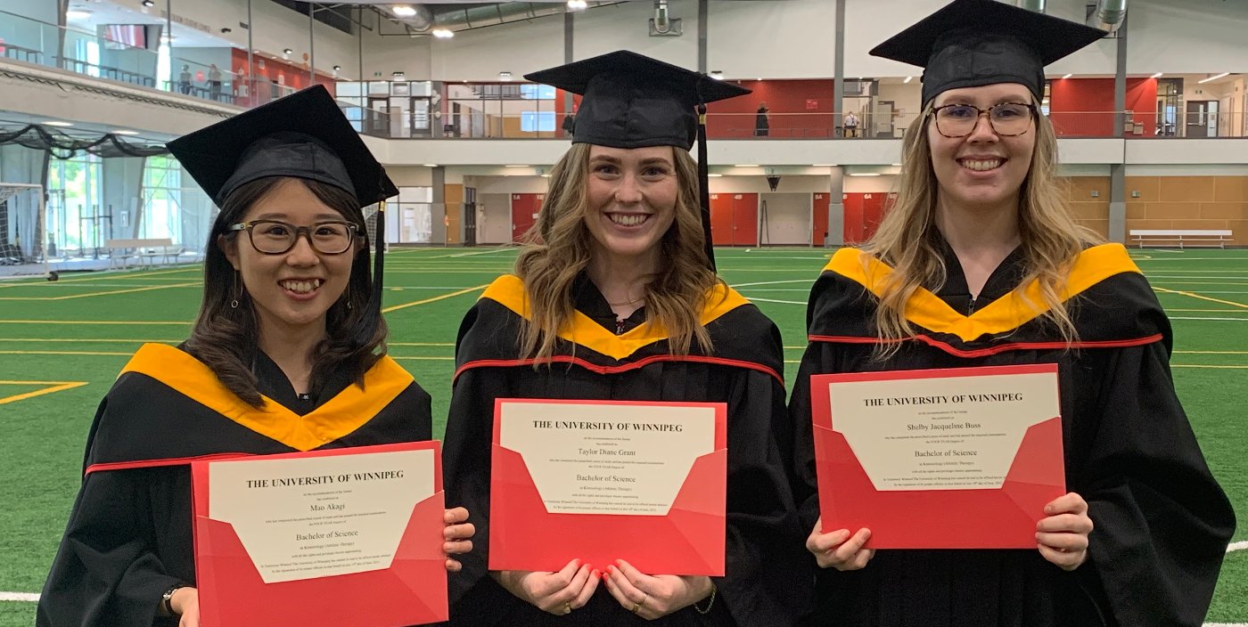 Three graduates stand alongside each other holding their degrees