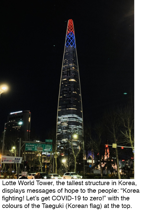 A tall building with blue and red lights at the very top.