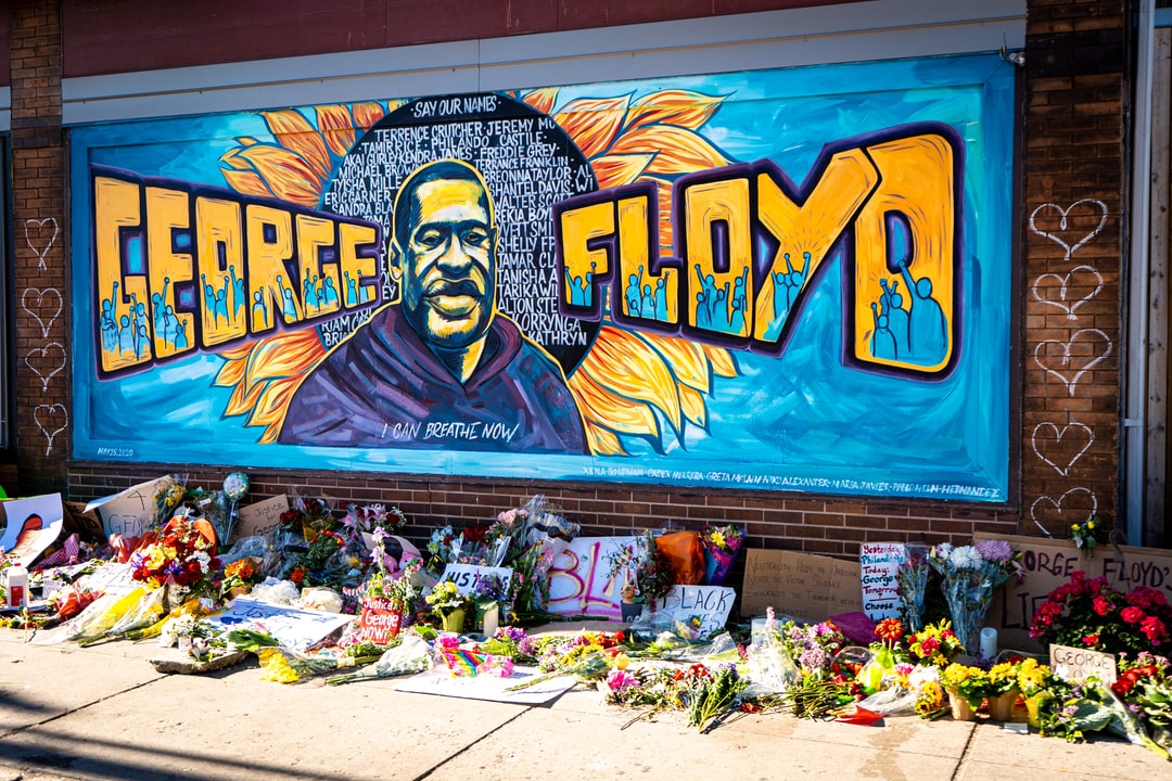 Painted mural portrait of George Floyd with bouquets of flowers in the foreground.