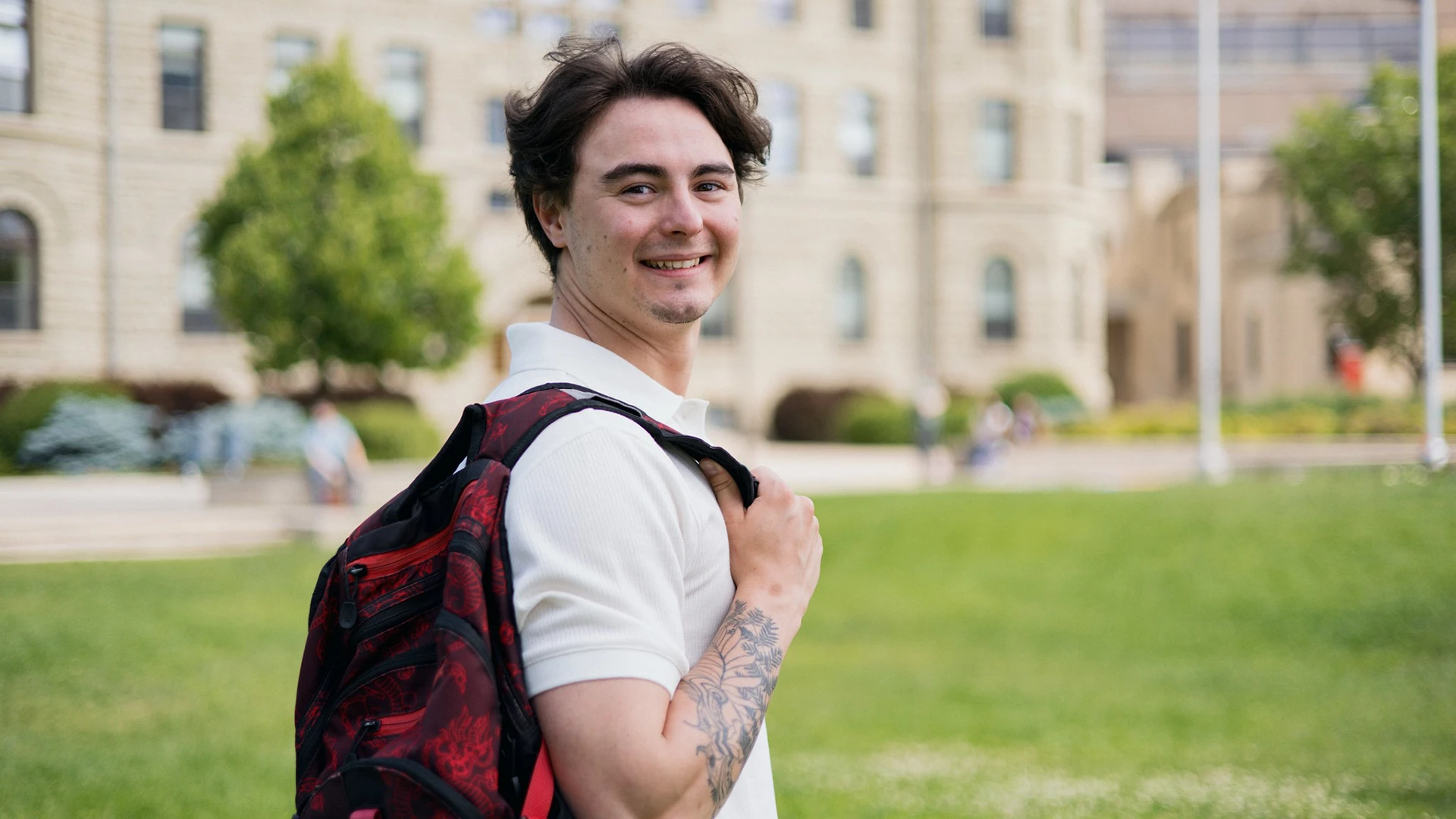 Student standing outside holding backpack