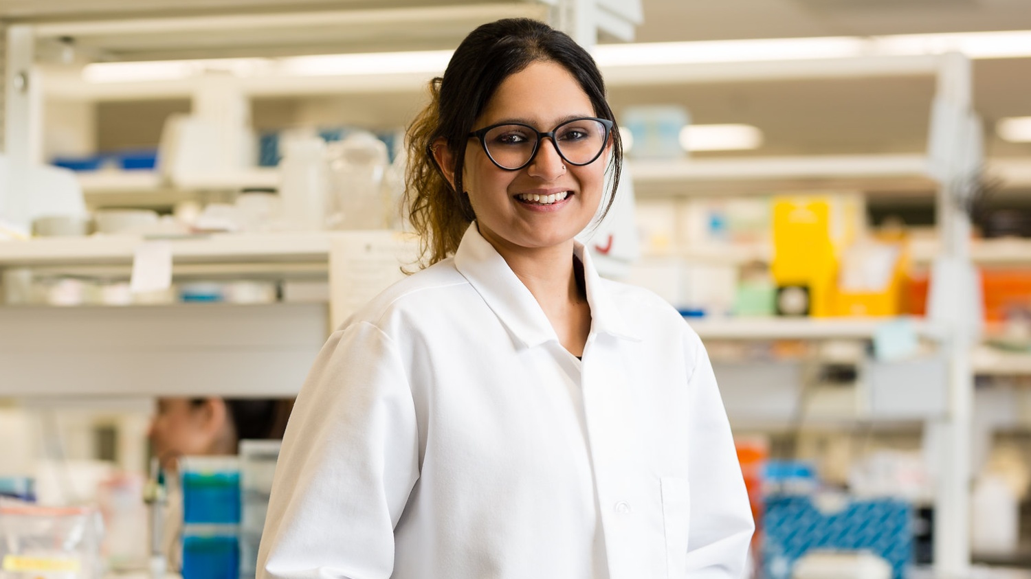 A smiling student in a lab coat
