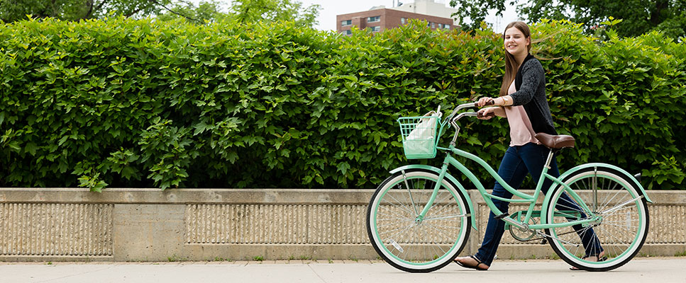 Student walking alongside bike outside