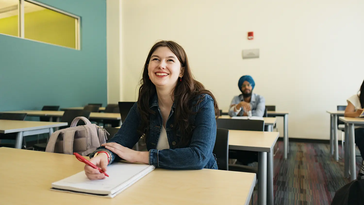 Student sitting in classs looking forward and smiling.