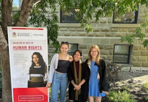 Three students stand beside a sign that says "Bachelor of Arts in Human Rights"