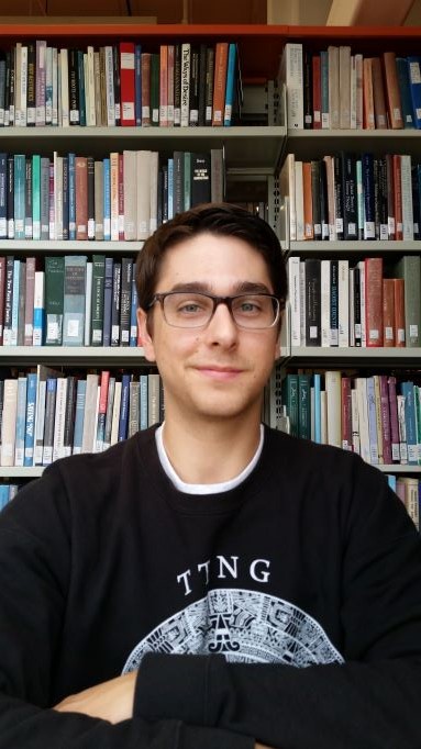 Blake Carter standing against a book shelf