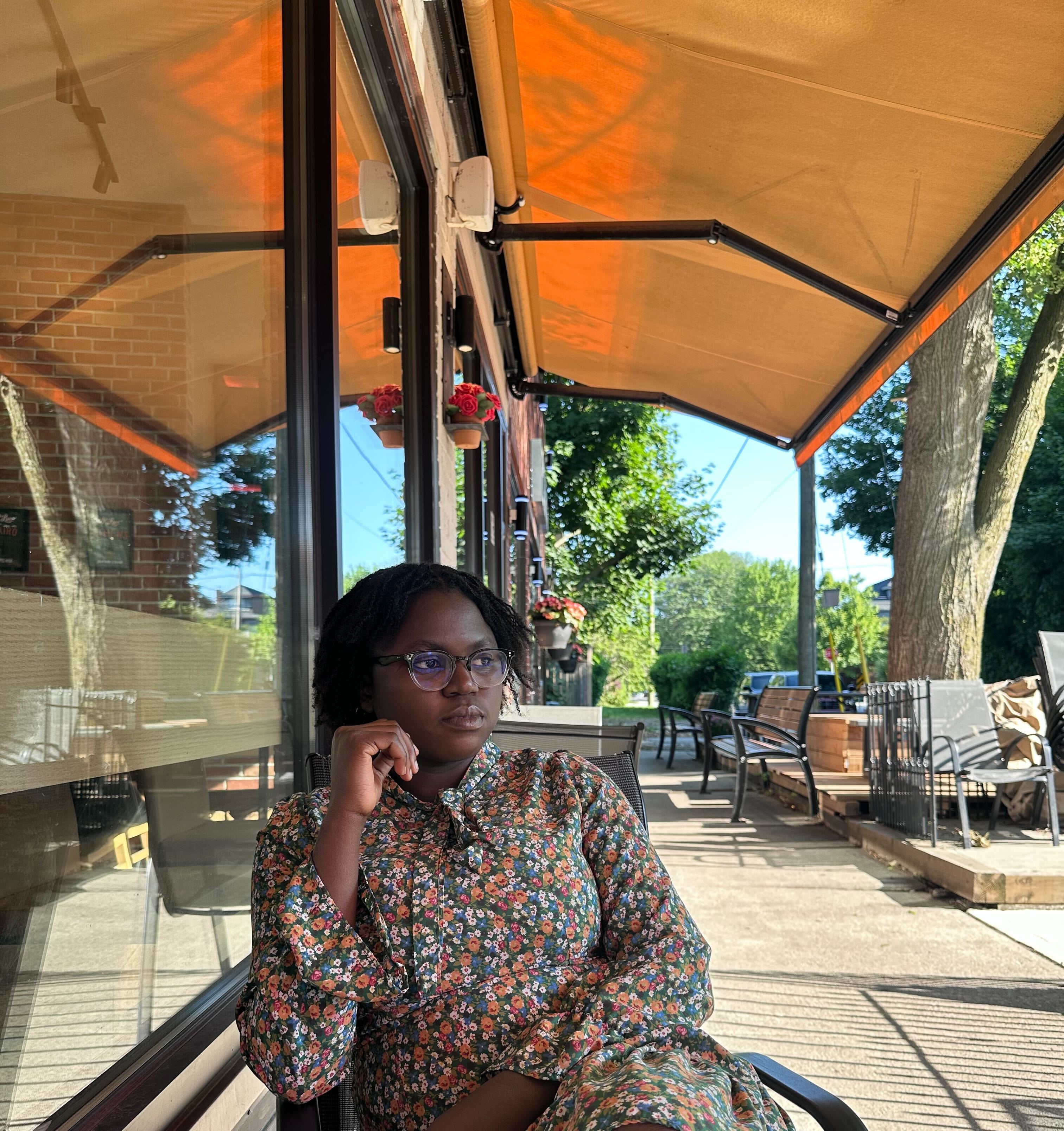 Faith Akinyemi sitting outside under an orange canopy