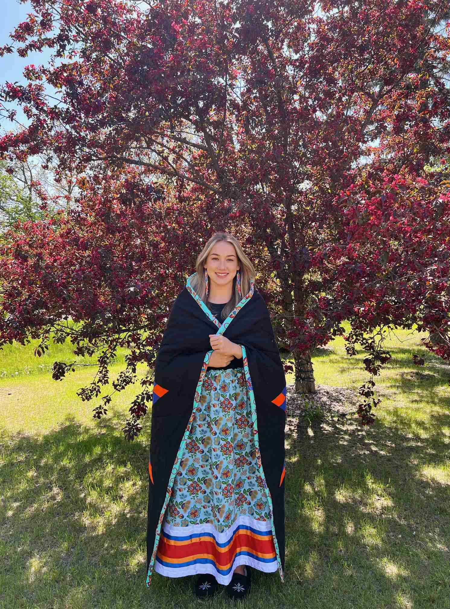 ISSP Scholar Erin Sinclair stands smiling and wrapped in a Star Blanket. 