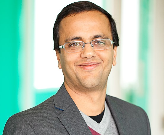 Photo of Manish Pandey, Acting Dean of Gradaute Studies. He is smiling in front of a blurred green and beige background.