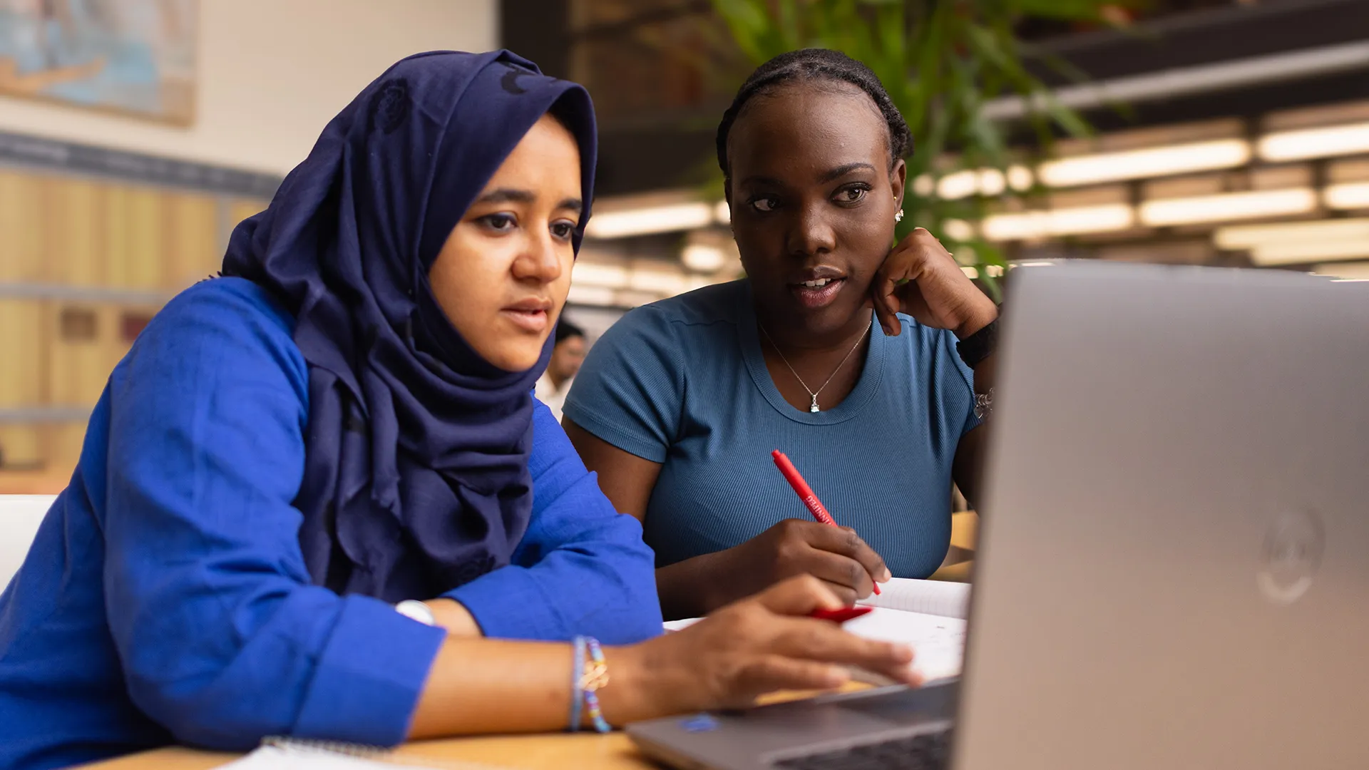 Two students working in front of a laptop