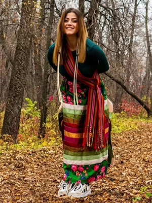 Jessica standing in the woods and wearing a ribbon skirt