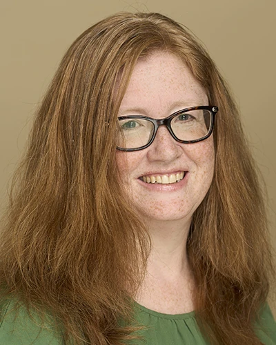 A headshot of Dr. Lisa Sinclair in front of a beige background.