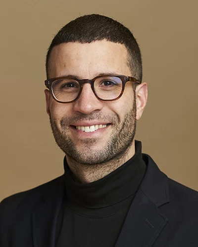 A headshot of Dr. Yannick Molgat in front of a beige background.