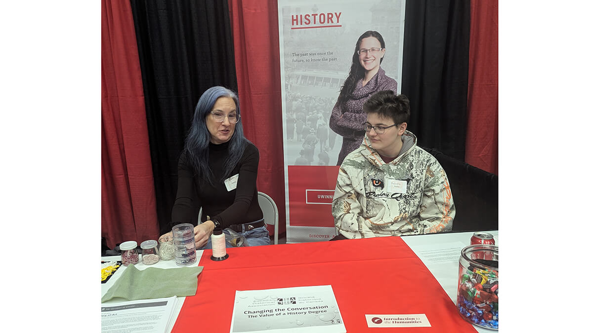 Two people sitting behind a table talking