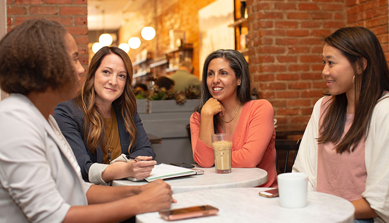 Four women at a table talking