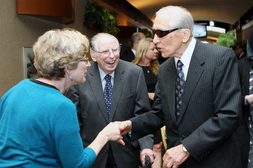 Three people at event, two shaking hands