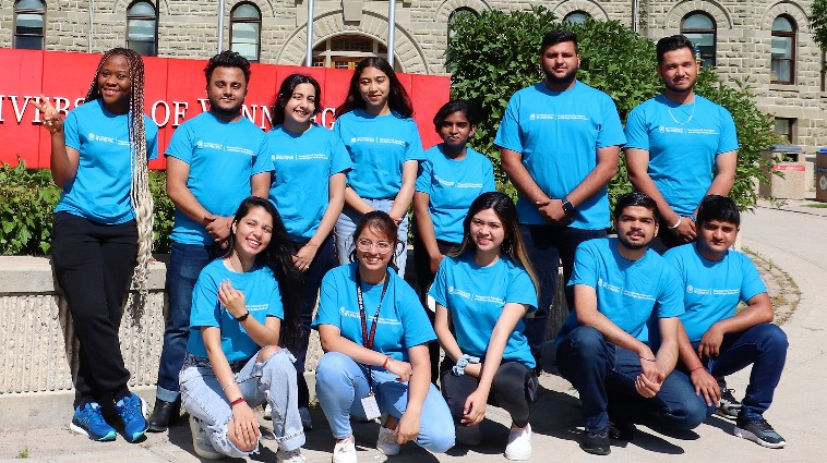 Group picture of student mentors wearing University of Winnipeg t-shirts in front of Wesley Hall.