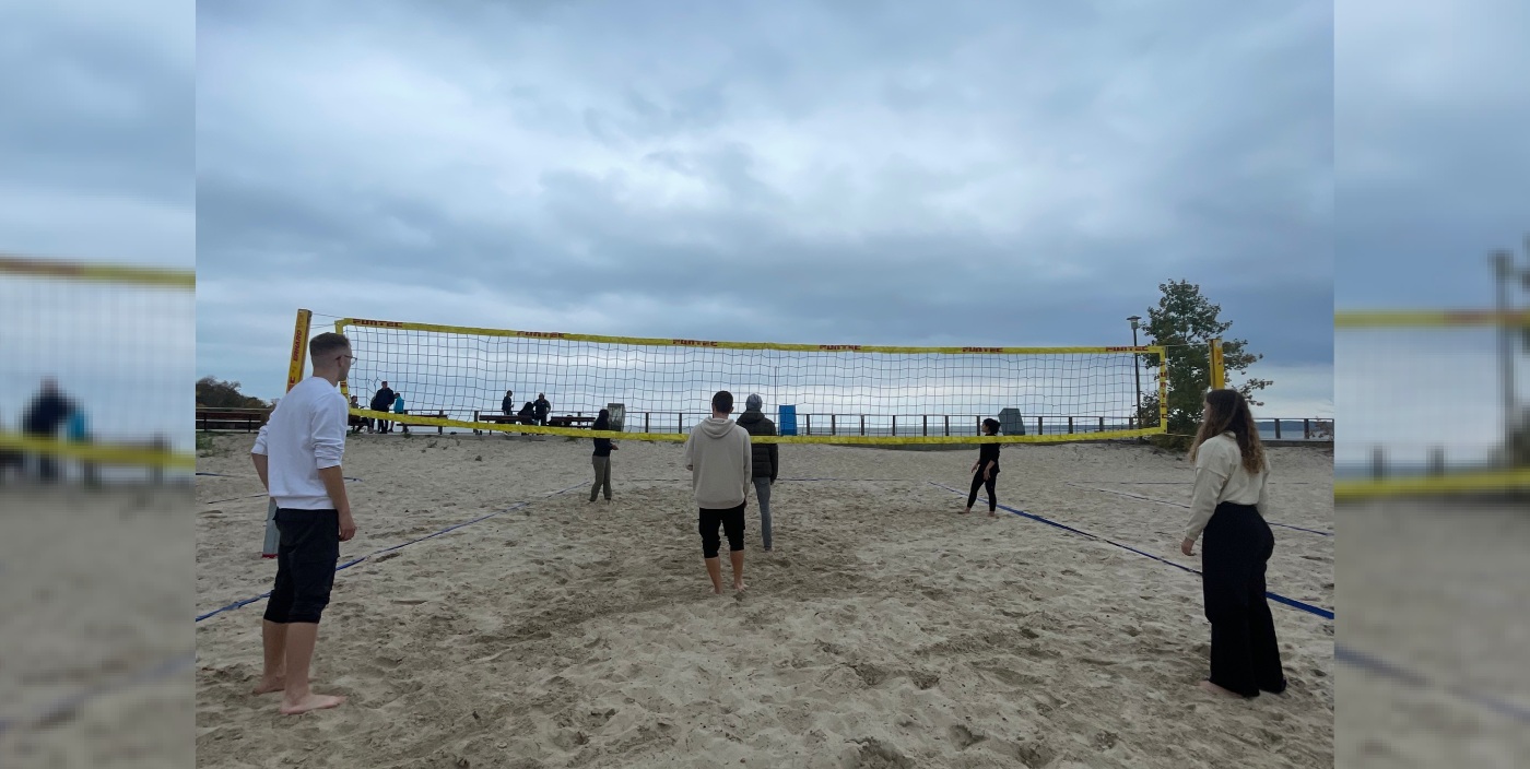 Several students play beach volleyball.