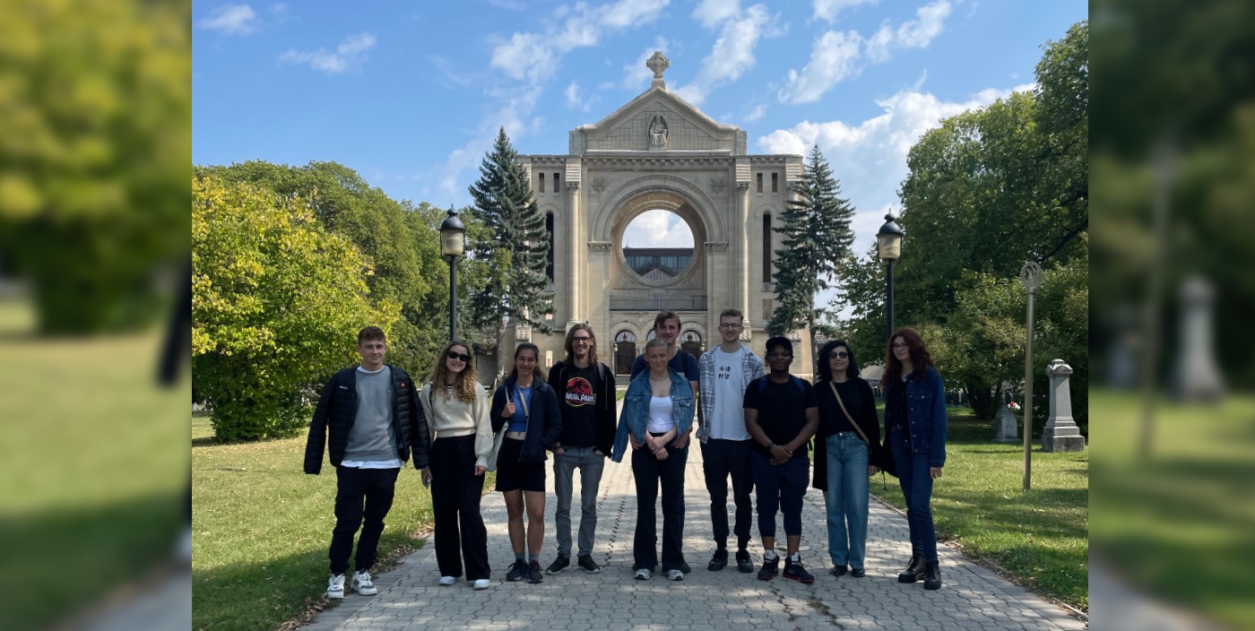 Students stand, smiling, in front of St. Boniface Cathedral.
