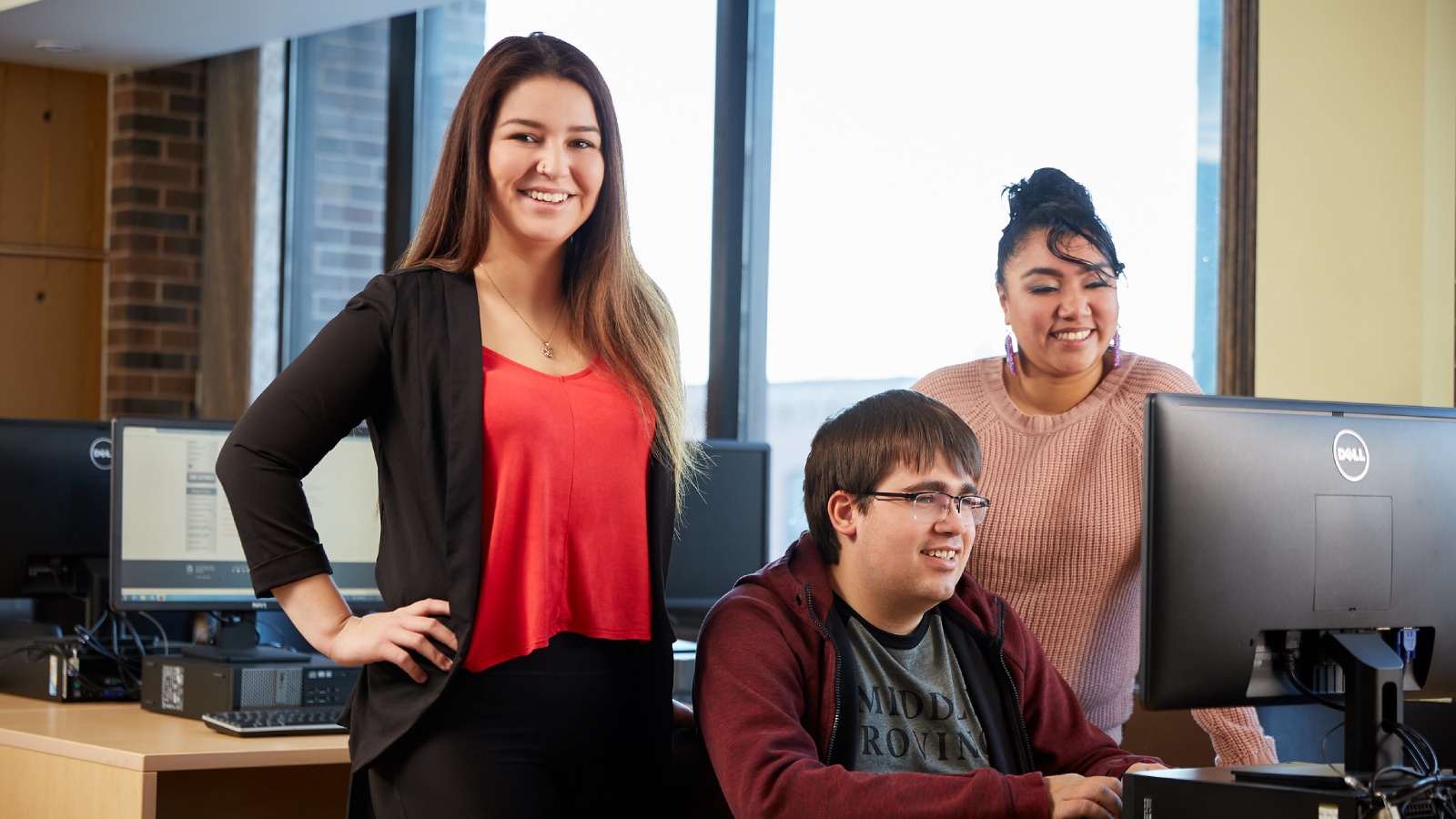 Three students stand at a computer