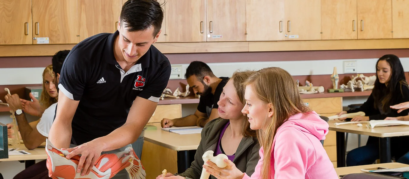 Students in a classroom looking at a muscles in a model of a leg